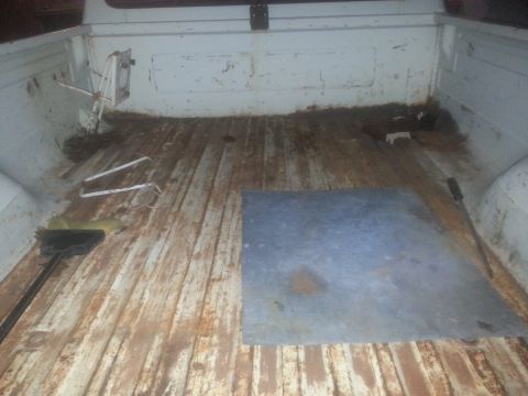1973 Ford F-100 - The bed of a pickup truck shows signs of wear and tear, with dirt and debris scattered across the wooden floor.