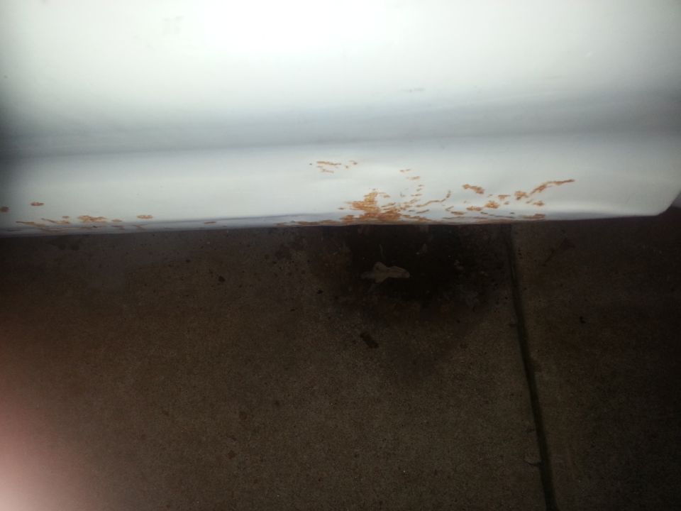 White vehicle lower body panel showing rust damage along the bottom edge