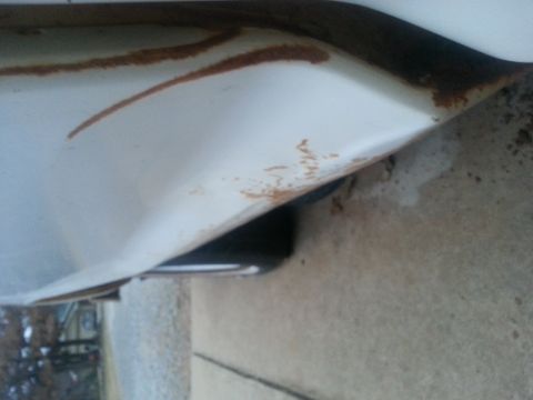 1973 Ford F-100 - Close-up view of a white truck fender showing signs of rust and a portion of a tire underneath.