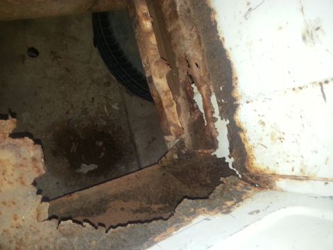1973 Ford F-100 - Severe rust damage is visible on the vehicle's frame and undercarriage, with a spare tire visible in the well.