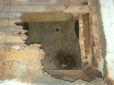 1973 Ford F-100 - The truck bed floor shows significant rust damage and a hole that exposes the spare tire underneath.