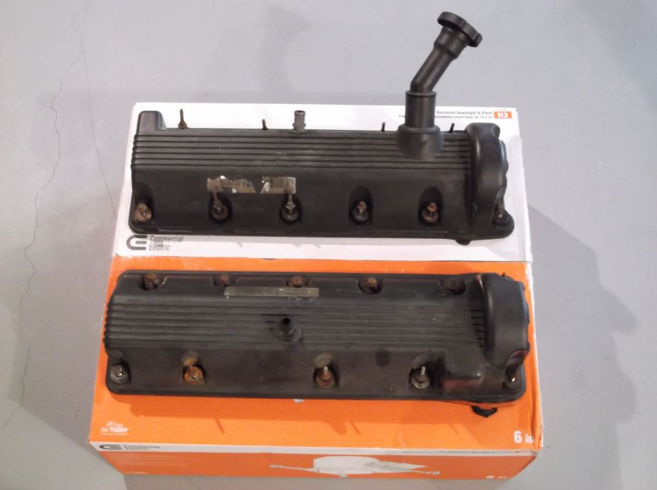 Two black engine valve covers stacked on an orange and white box