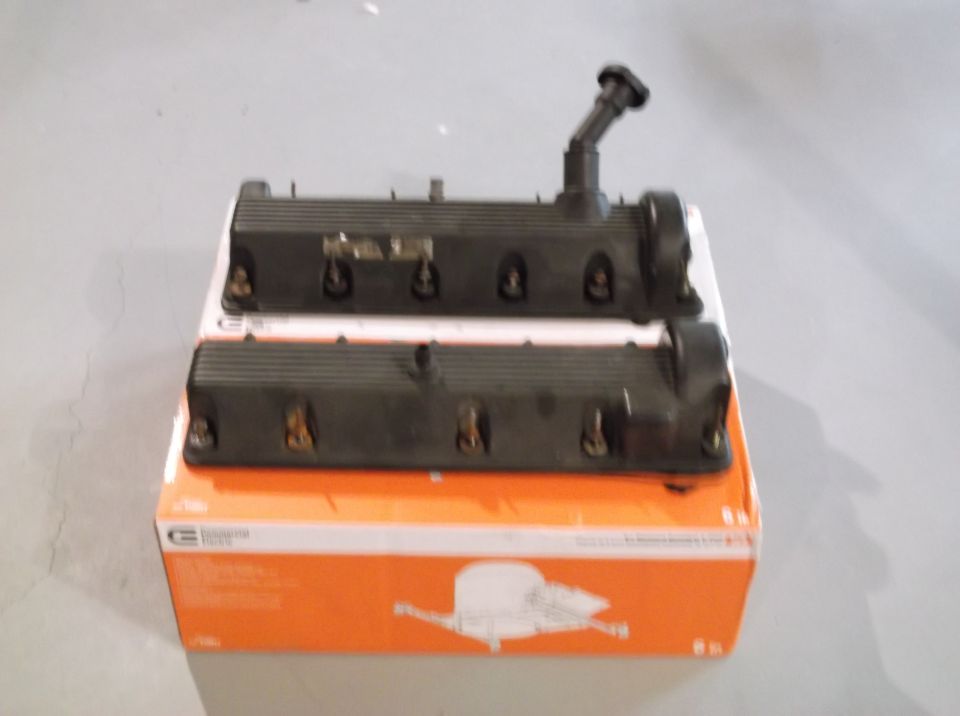 Two black engine valve covers stacked on an orange box