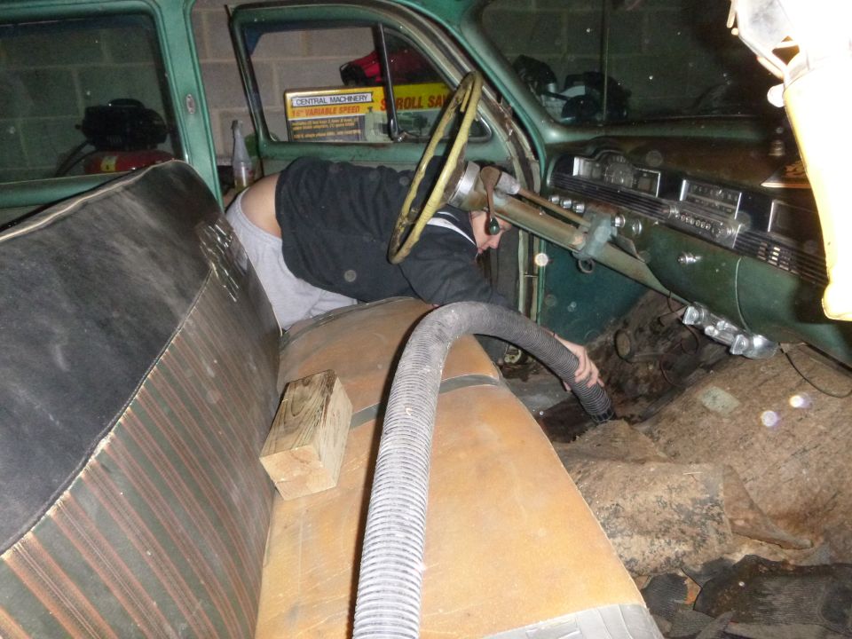 1953 Plymouth Belvedere interior with a person vacuuming the floor