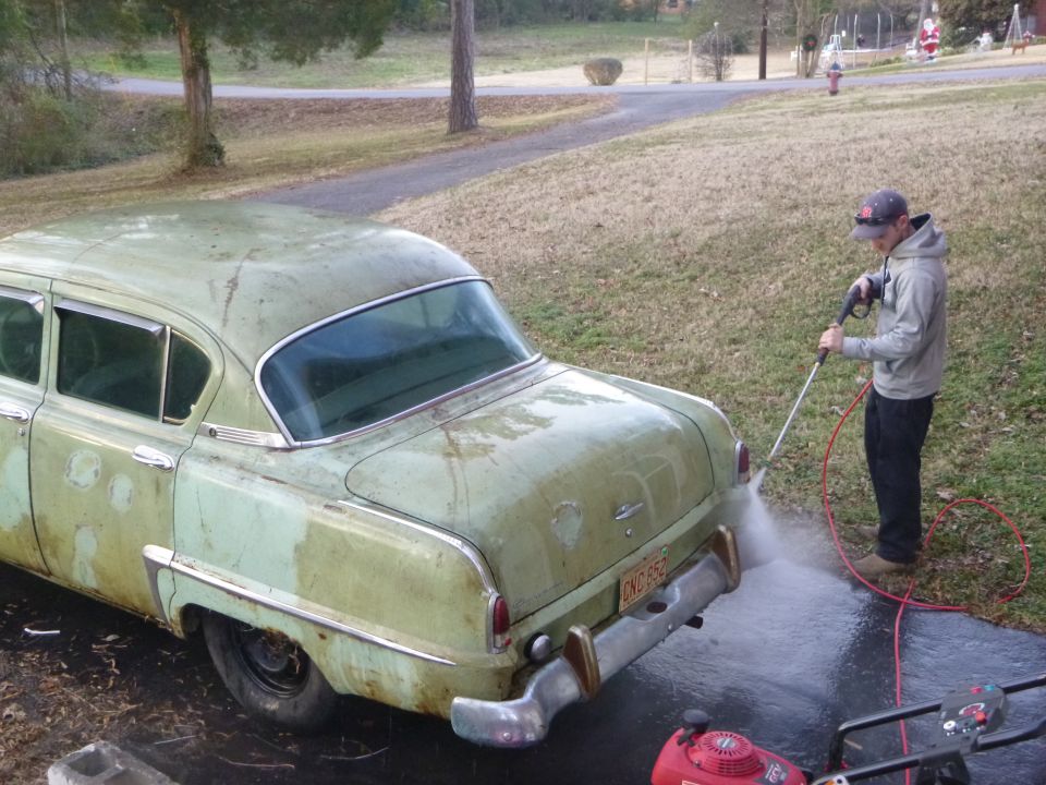 guy pressure washing a faded green 1953 Plymouth Belvedere