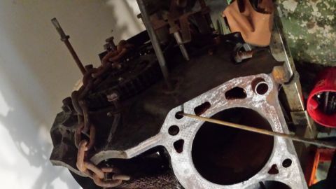 1995 Ford Bronco - Close-up view of an engine block and a gasket, with a tool inserted into a cylinder.