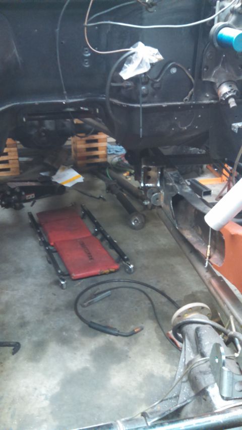 1967 Ford F-250 - The underside of a vehicle is shown, with various mechanical components and a red creeper on the floor.