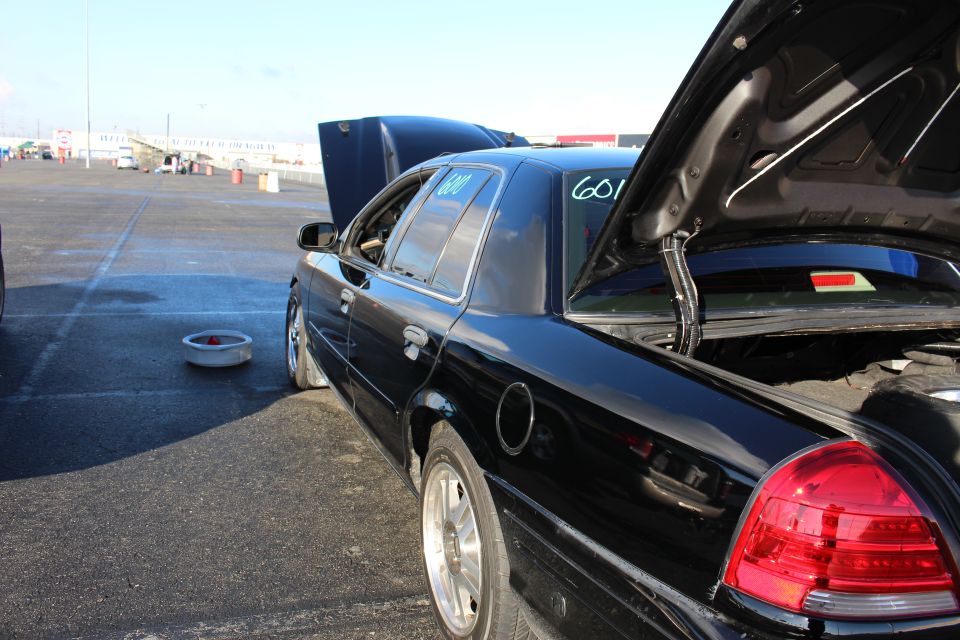 Rear quarter of a black sedan with trunk and hood open and racing number on glass