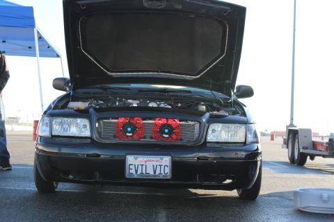 2003 Ford Crown Victoria - Close front view of a black sedan with open hood revealing two red round air filters and a California EVIL VIC license plate.