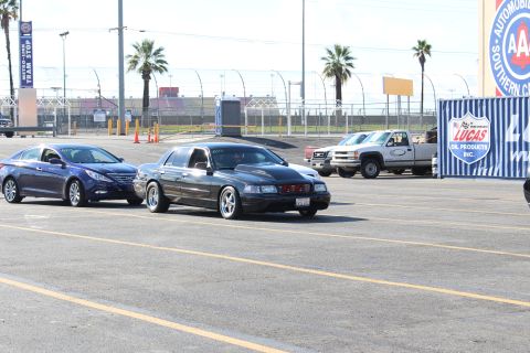 2003 Ford Crown Victoria - blue sedan and a black sedan parked in a lot with a pickup, AAA emblem and Lucas Oil signage in the background.