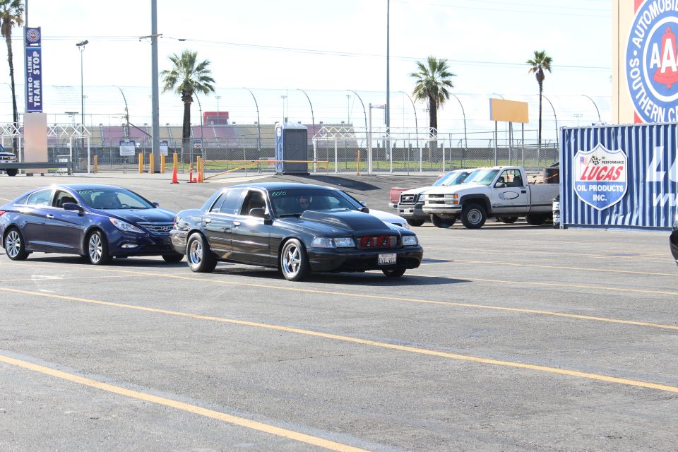 Blue sedan and black sedan parked near AAA and Lucas Oil signs in lot