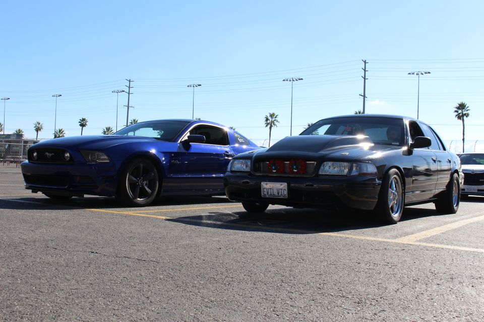 Front three-quarter of blue Mustang and black Ford sedan with red air filters