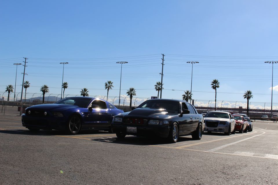 Blue Mustang, black sedan and silver Chrysler 300 parked in a row under blue sky with palm trees