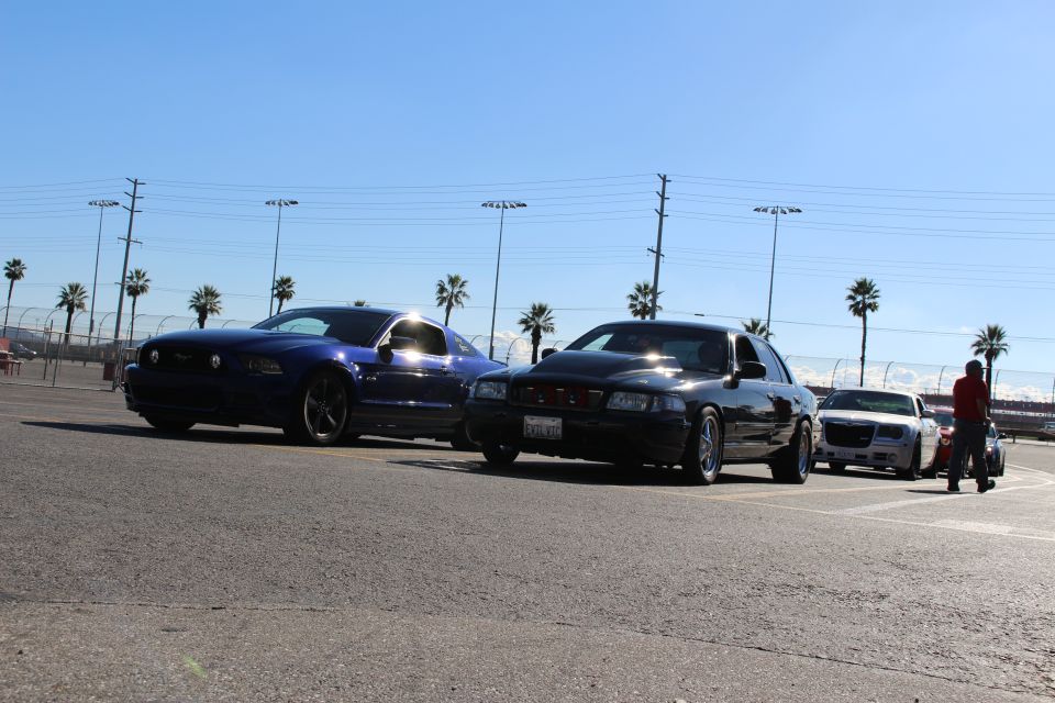 Blue Mustang, black sedan and silver Chrysler 300 in a lot with a person in red walking at right