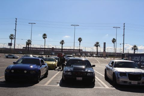 2003 Ford Crown Victoria - blue coupe, a black sedan, and a silver Chrysler 300 are parked facing forward in a sunny dragstrip parking lot.