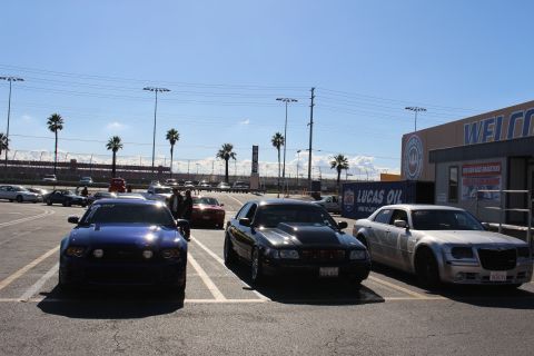 2003 Ford Crown Victoria - blue car, black sedan, and silver Chrysler 300 are parked outside a building with a Welcome sign at a sunny dragstrip.