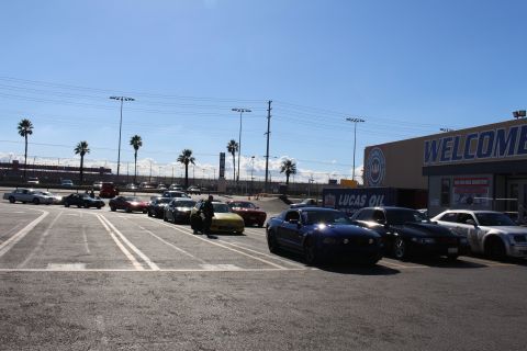 2003 Ford Crown Victoria - black Mustang and several other cars are parked across a sunny dragstrip lot beside a WELCOME building and Lucas Oil sign.