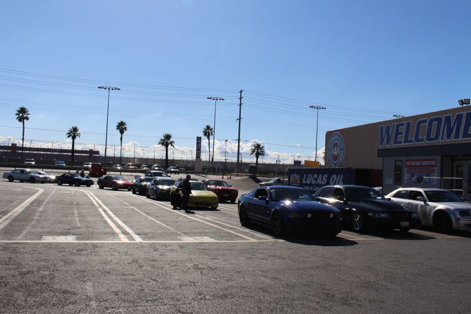 Black Mustang and other cars parked in a sunny lot beside a WELCOME building