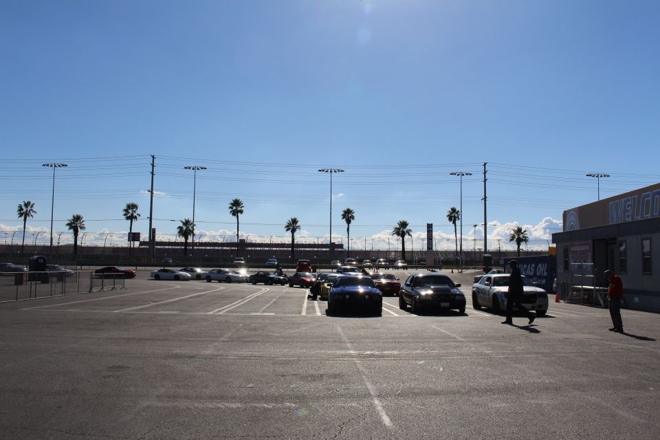 Wide parking lot with parked cars, people walking and a WELCOME building on the right