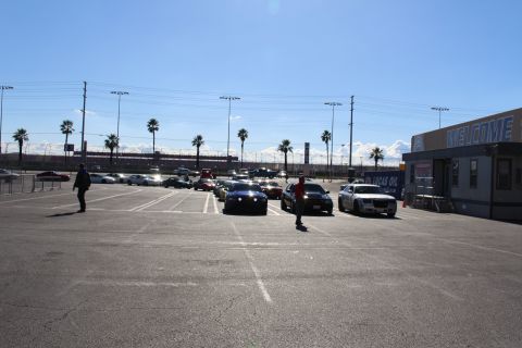 2003 Ford Crown Victoria - Several people walk among parked cars in a sunny dragstrip lot beside a WELCOME building and Lucas Oil signage.