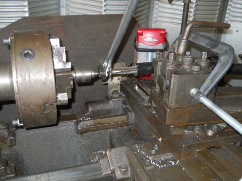 1992 Ford Bronco - A close-up view of a part being machined on a lathe, with a wrench in operation and a red weather radio visible.