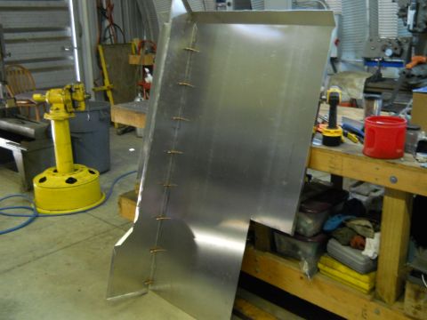 1992 Ford Bronco - A custom-fabricated sheet metal piece is shown in a workshop, with various tools and storage bins visible in the background.