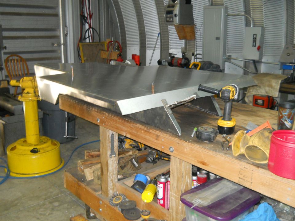 Metal sheet on workbench with tools, yellow vise, and Supermotors logo