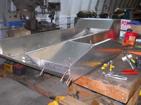 1992 Ford Bronco - An unfinished aluminum boat hull sits on a workbench, surrounded by tools and shop equipment.