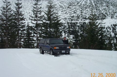 1995 Ford Bronco - A person stands next to a Ford Ranger pickup truck in a snowy, wooded area.