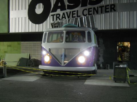 1992 Ford Bronco - A purple and white van with flower decals on the front is parked in front of a building with a sign that reads "OASIS TRAVEL CENTER". A cat…