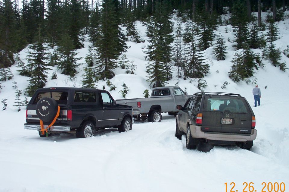 Black Ford Bronco with spare tire on rear, stuck in snow