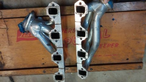 1995 Ford Bronco - A pair of polished exhaust manifolds are laid out on a wooden surface. The manifolds have rectangular ports and appear to be for a V8 engin…