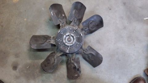 1995 Ford Bronco - A black engine cooling fan with eight blades is shown lying on a concrete floor. The fan has a silver central hub with visible ribs and som…