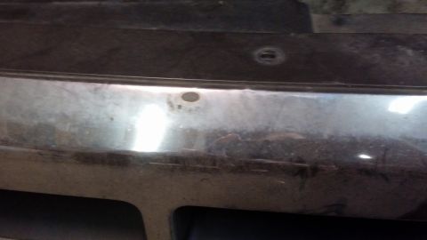1995 Ford Bronco - A close-up view of the front bumper of a vehicle, showing two parking sensor holes. The bumper appears to be chrome with some scuffs and di…