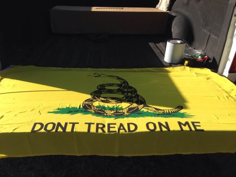 1979 Ford Bronco - A Gadsden flag with the phrase "DONT TREAD ON ME" is laid out in the bed of a pickup truck. A roll of tape and some other items are visible…
