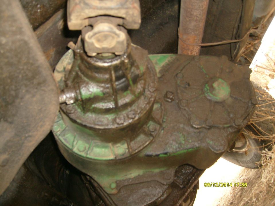 Mud-covered green transfer case assembly with visible universal joint.