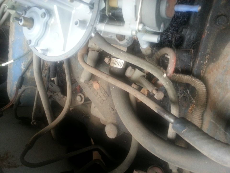 Close-up of a vintage engine bay with carburetor, hoses, and wiring.