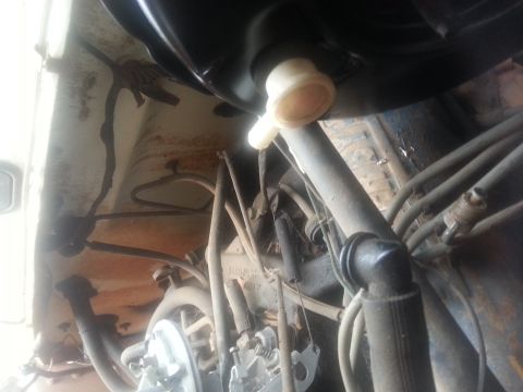 1973 Ford F-100 - A low-angle shot looking up at the underside of a vehicle, showing various hoses, wires, and mechanical components. A black tank is visible…