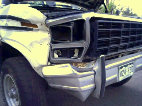 1981 Ford Bronco - The front of a severely damaged truck shows a broken headlight and grille, with a license plate visible.