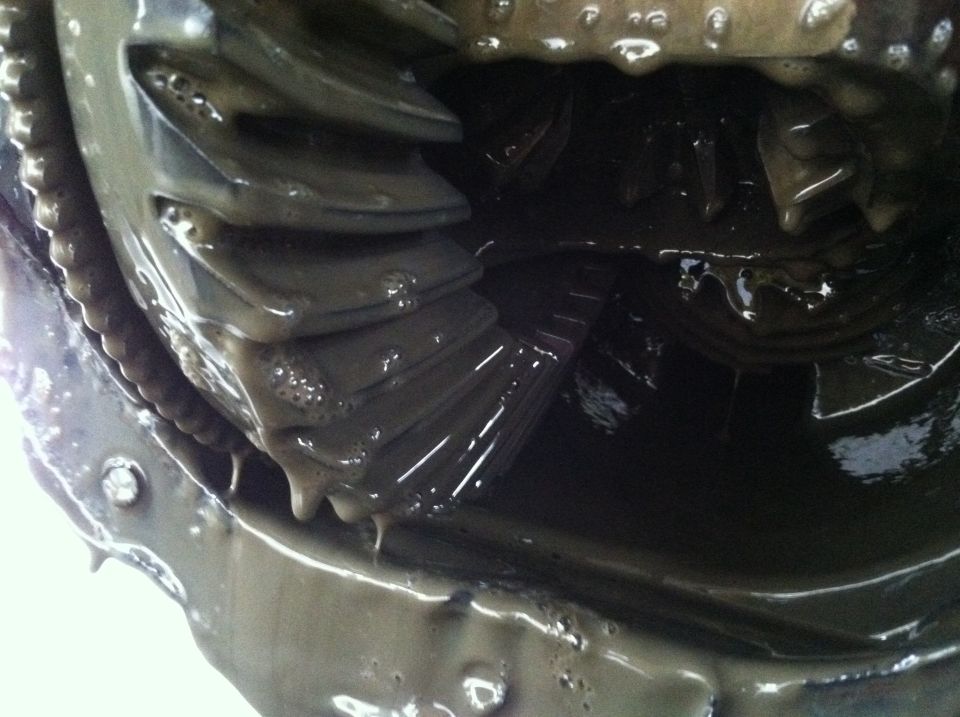 Close-up of worn differential gears in a 1996 Ford Bronco, covered in dark, sludgy fluid.
