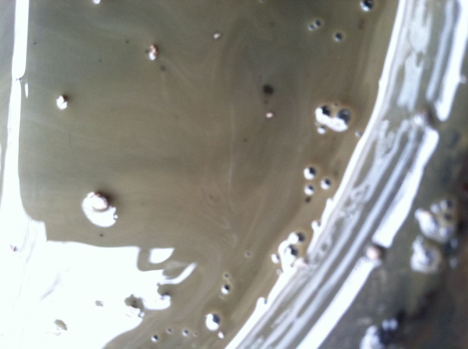Close-up of murky liquid with bubbles and reflections.