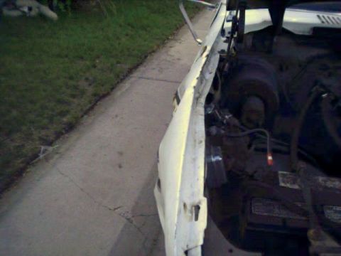 1981 Ford Bronco - The engine bay of a damaged white vehicle is visible, with a Supermotors.net logo in the lower right corner.
