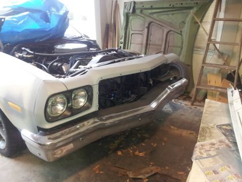 1976 Ford Ranchero - A white 1970s era pickup truck, possibly a Ford Ranchero, is in a garage with its hood open and engine exposed. The front bumper and headli…