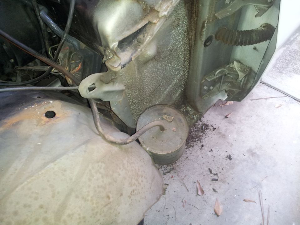 Close-up of vehicle engine bay and fender area with mechanical parts and wiring.