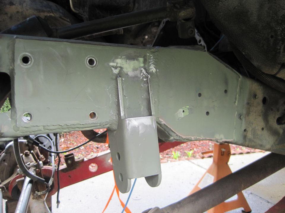 Photo of a green-primed welded frame crossmember and shackle mount under a vehicle