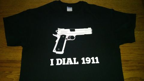 1979 Ford Bronco - A black t-shirt with a white outline of a handgun and the text "I DIAL 1911" printed on it.