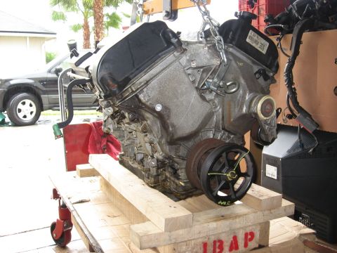 1994 Ford Bronco - Engine being hoisted, with a dark SUV in the background.