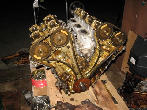 1994 Ford Bronco - A disassembled V8 engine with gold-colored components and timing chains is laid out on wooden planks. Various engine parts and containers o…