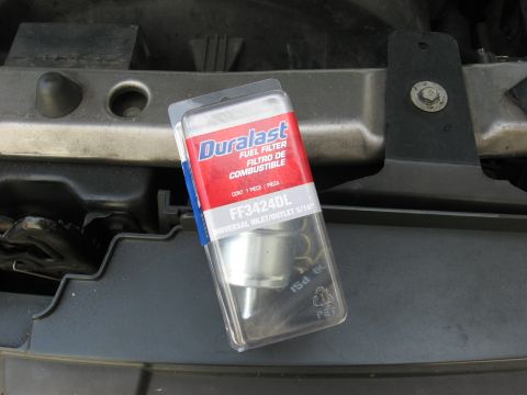 1994 Ford Bronco - A Duralast FF3424DL fuel filter in its original packaging rests on a dark gray textured surface, likely under the hood of a vehicle.