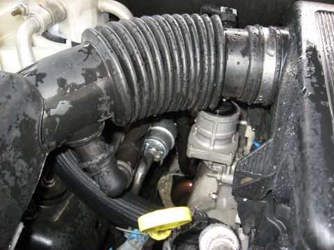 1994 Ford Bronco - A close-up view of the engine bay of a 1994 Ford Bronco, focusing on the corrugated rubber intake hose and various engine components. The e…